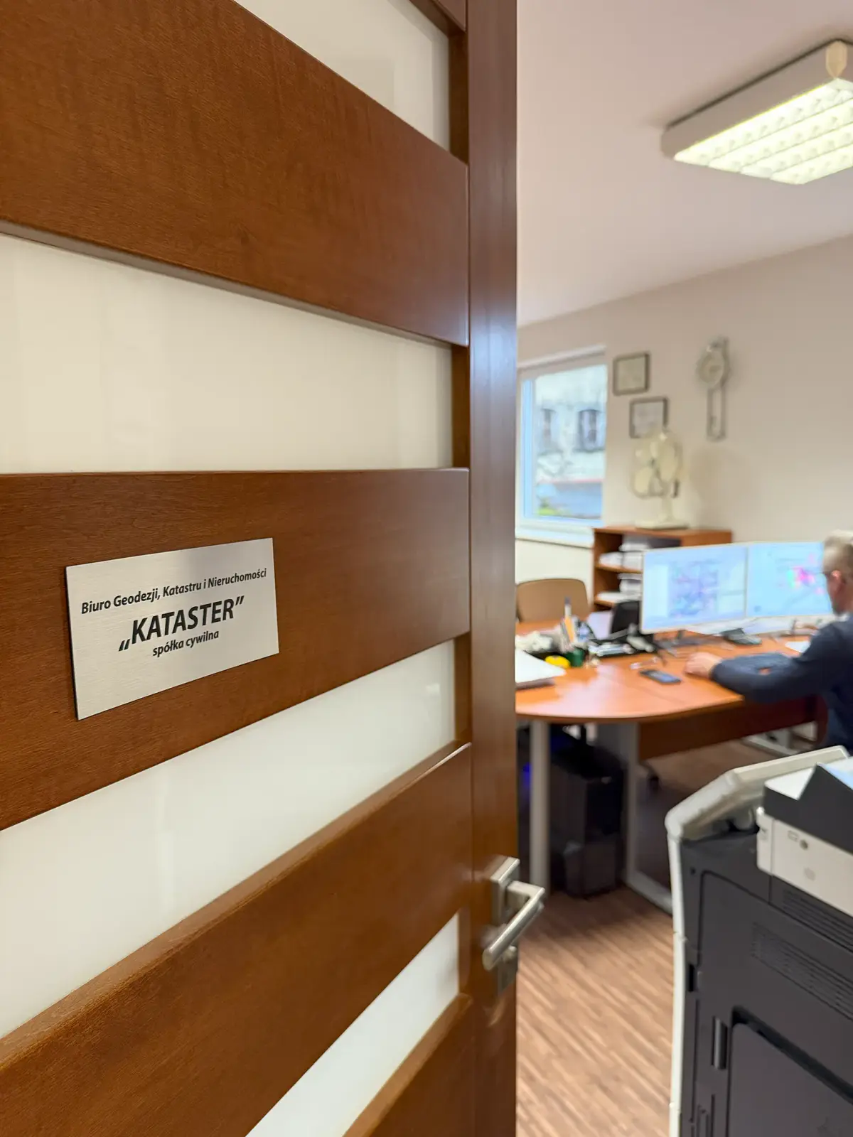 Tabliczka na drzwiach biura: Biuro Geodezji, Katastru i Nieruchomości „Kataster” spółka cywilna